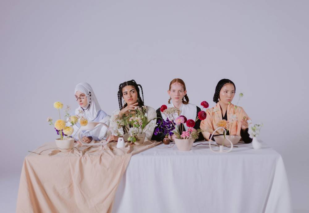 four women at a table in front of flowers