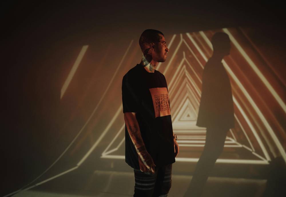 man in front of a wall with a projector showcasing triangle shapes in the dark